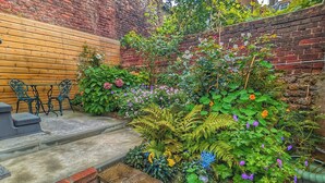 A brick wall with a wooden bench and a small table. - Sea Spray (Brighton)