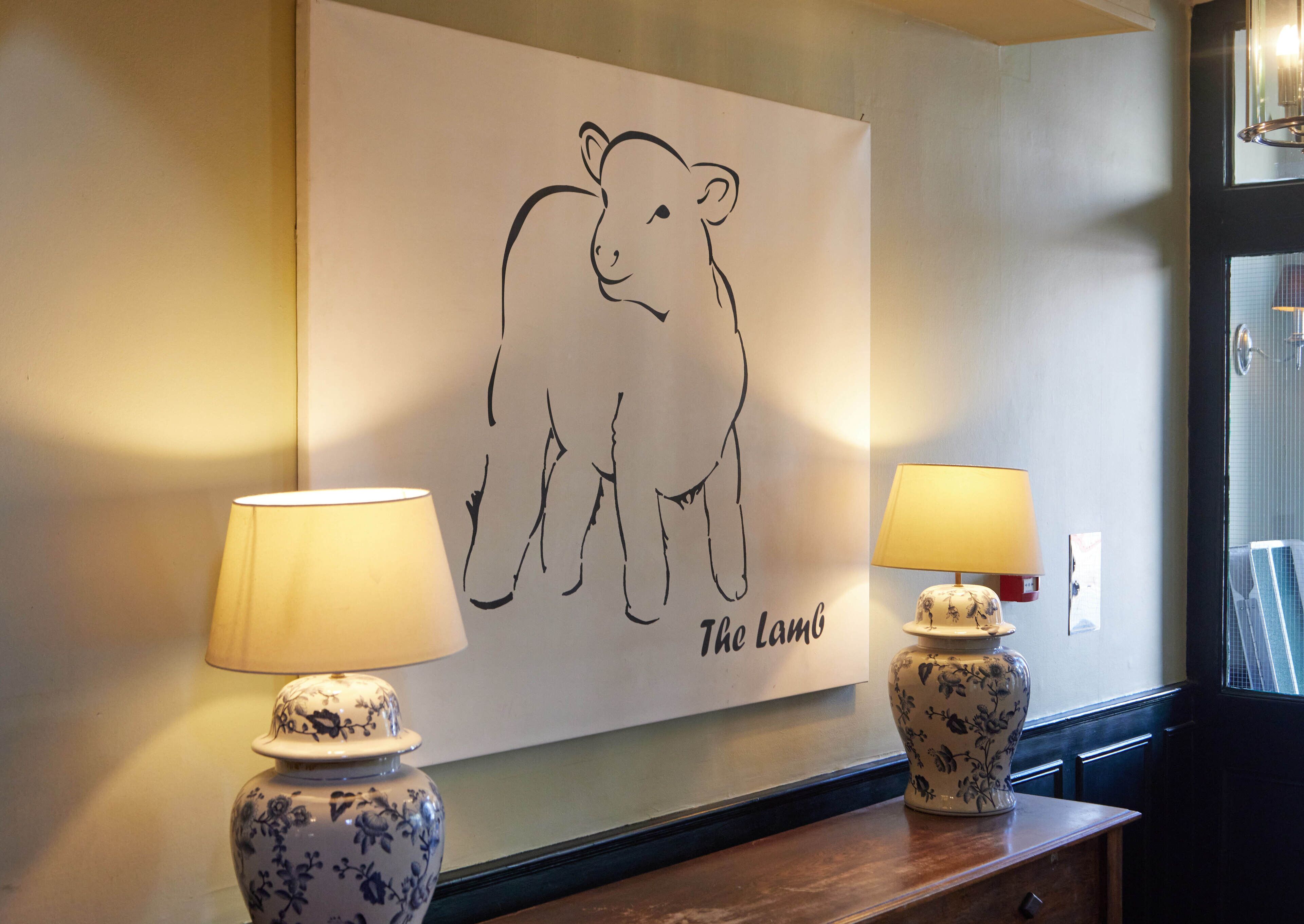 A wall with a bear illustration and the text "The Lamb" above two lamps with floral designs.