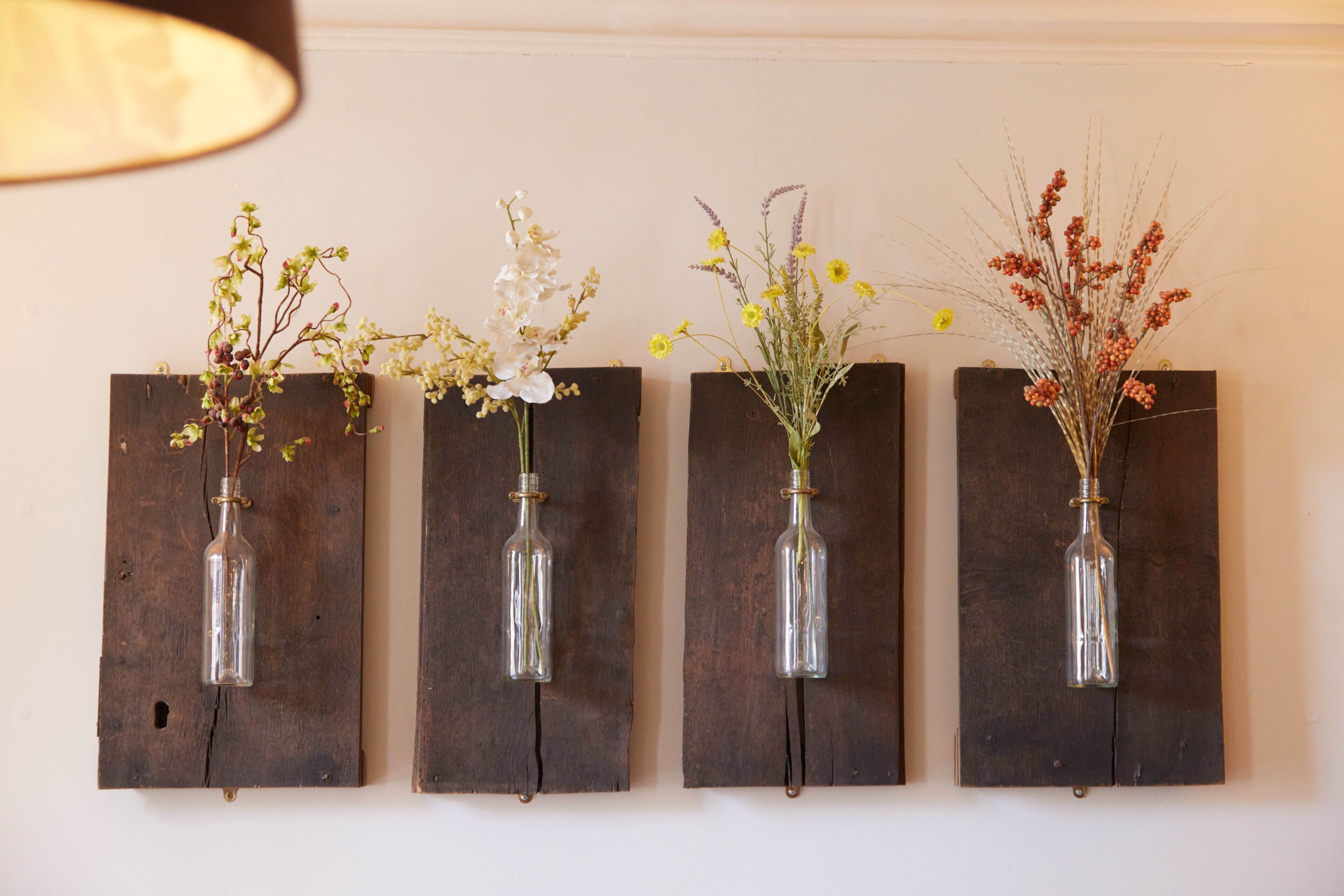 Four wall-mounted vases with different flowers.