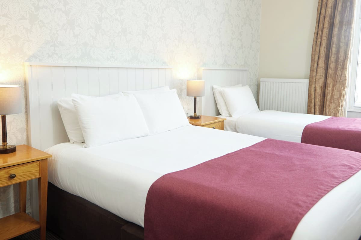 A hotel room with two beds, each with white bedding and a wooden nightstand.