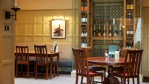 Un comedor con mesas y sillas de madera, un letrero de recepción y una exhibición de vinos.