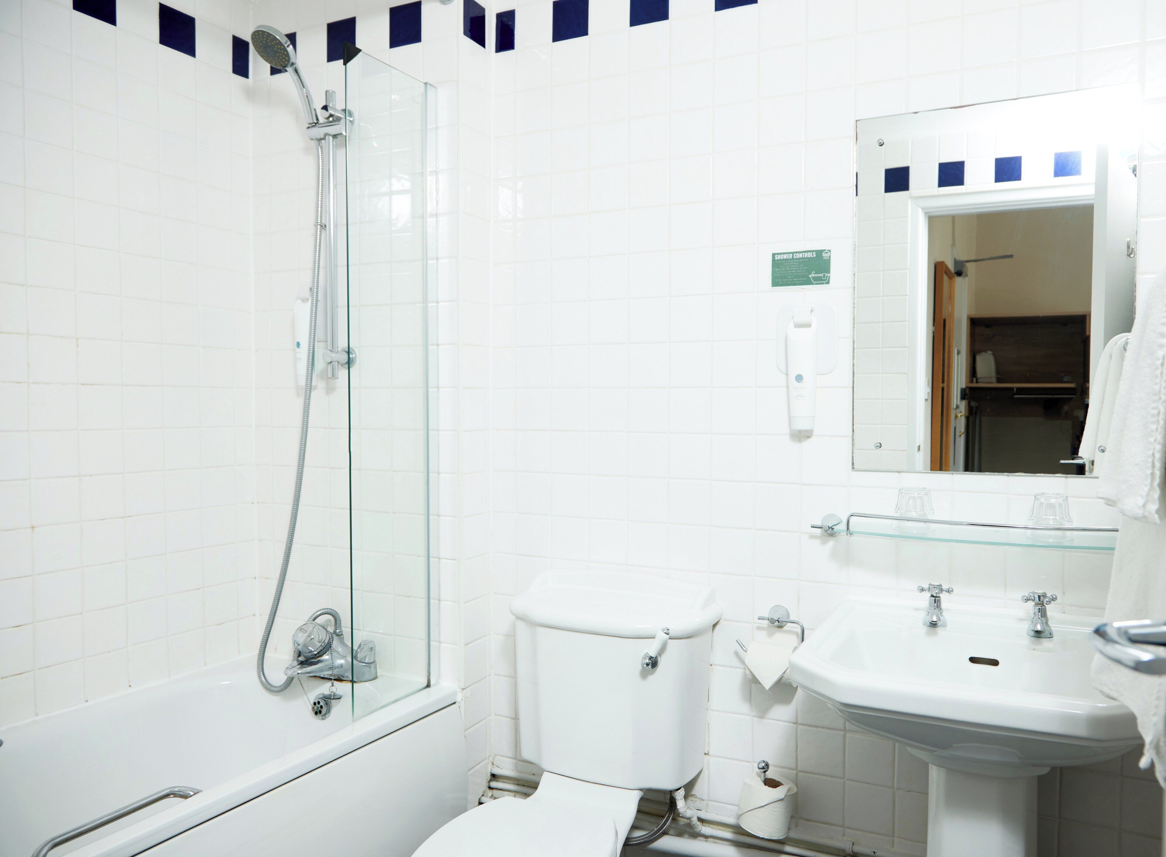 Un bagno con cabina doccia in vetro, un water bianco e un lavandino con uno specchio sopra.