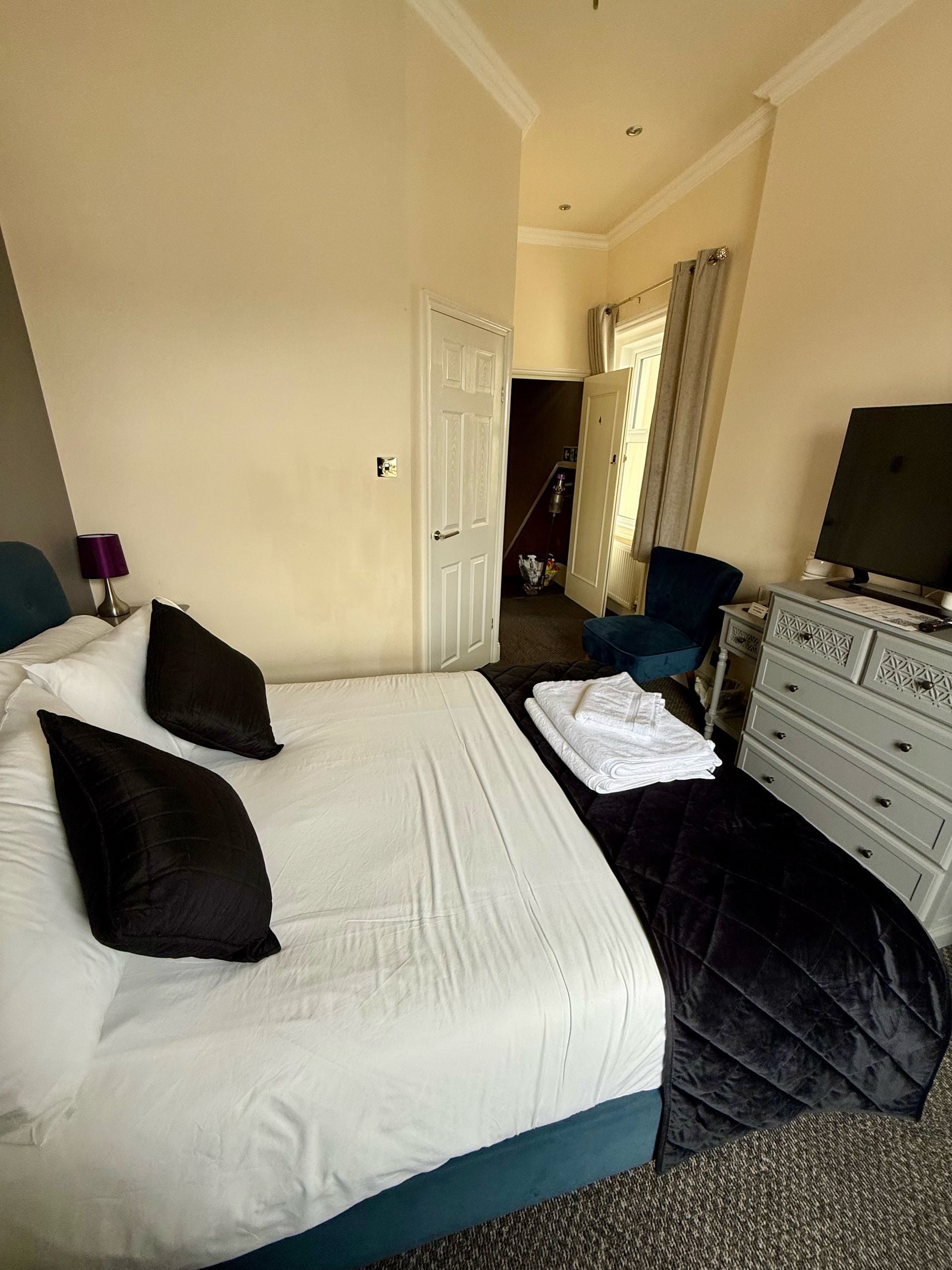 A hotel room with a bed, a dresser, a chair, and a desk with a computer.