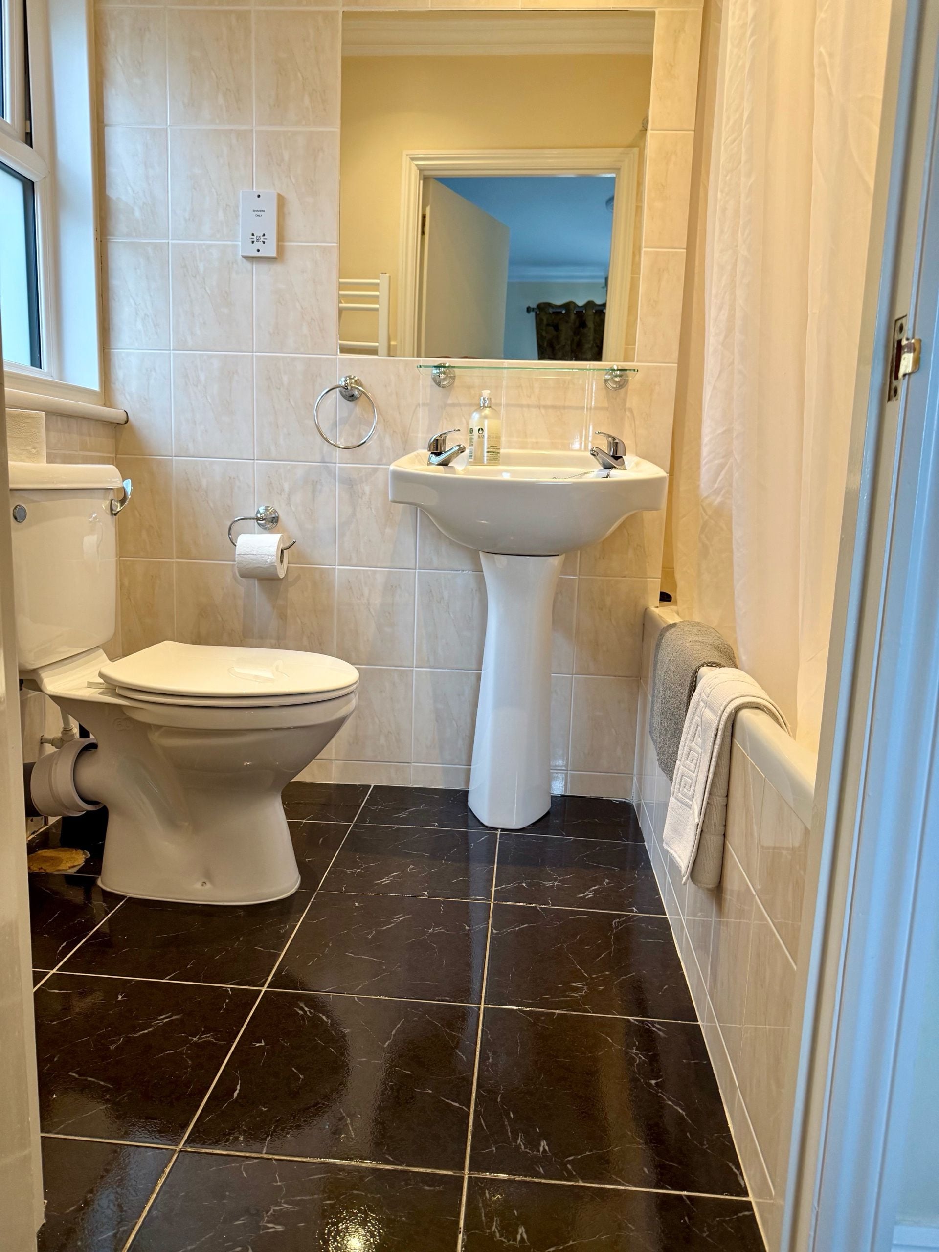 Une salle de bain équipée de toilettes, d’un lavabo et d’un porte-serviettes.