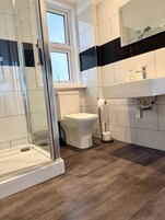 Ein modernes Badezimmer mit einer Duschkabine, einer Toilette und einem Waschbecken mit Spiegel.