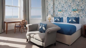 A hotel room with a large bed, a sofa, a desk, and a view of the sea. - The Cumberland Hotel (Eastbourne)