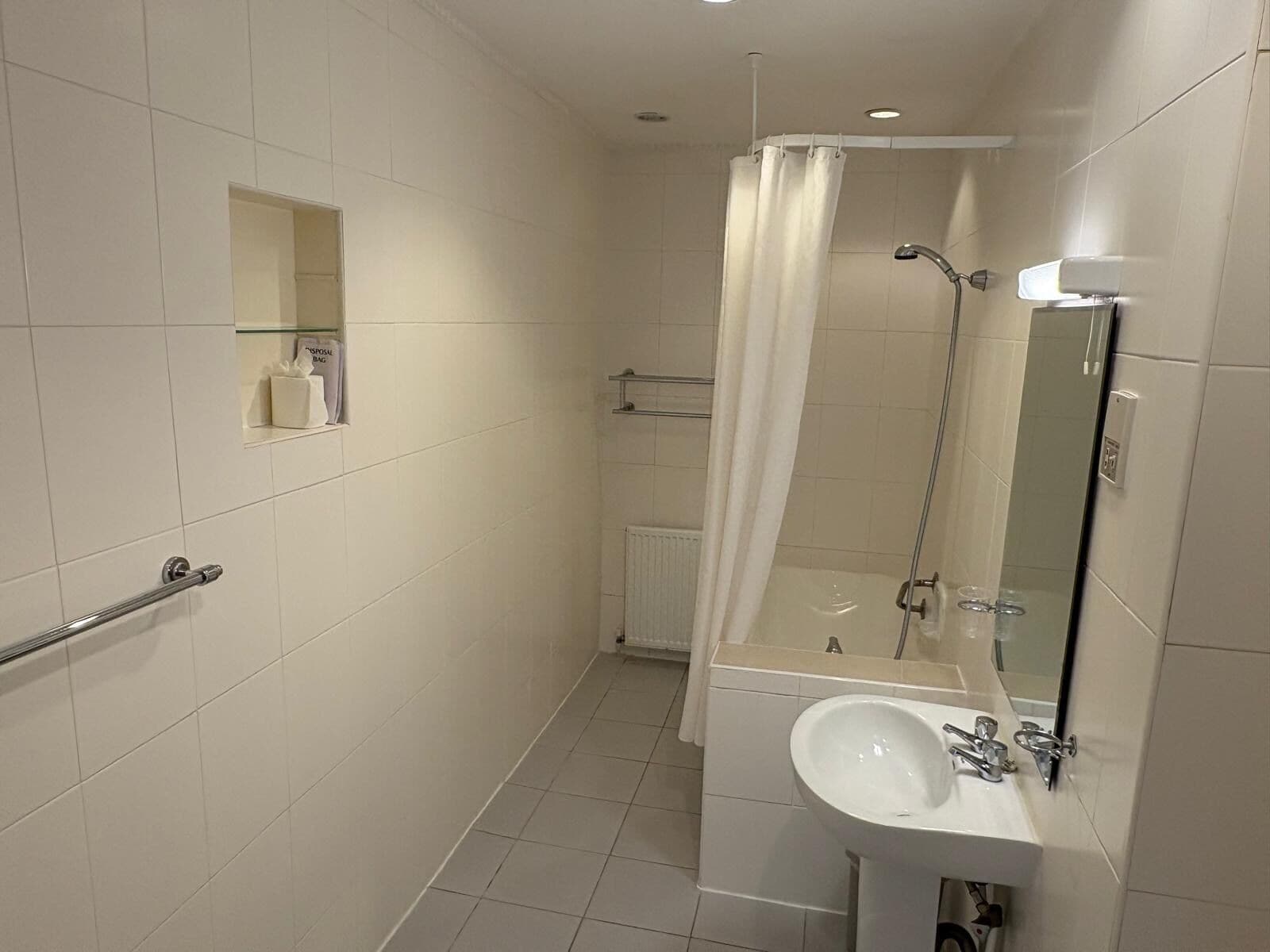 Un baño moderno con ducha, lavamanos, espejo y toallero.