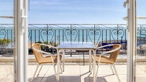 A balcony with a table and two wicker chairs, overlooking a body of water. - The Cumberland Hotel (Eastbourne)