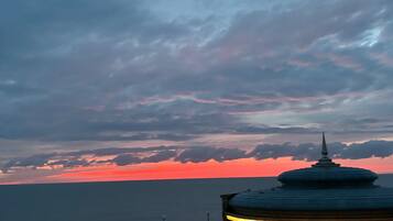 A coastal sunset view with a gazebo and a railing.