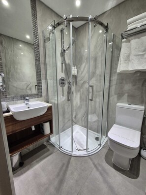 A modern bathroom with a glass-enclosed shower, a sink, and a toilet. - London Court Hotel (London)
