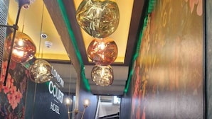 A modern hotel interior with a staircase, decorative lighting, and floral wall art. - London Court Hotel (London)