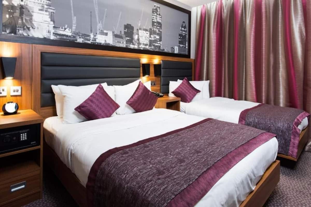 A hotel room with two beds, a cityscape view, a wooden headboard, and a nightstand with a clock.