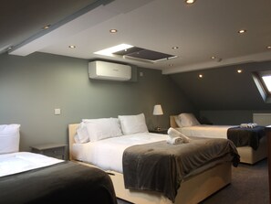 A modern hotel room with two beds, a ceiling fan, recessed lighting, and a skylight. - St Simeon (London)