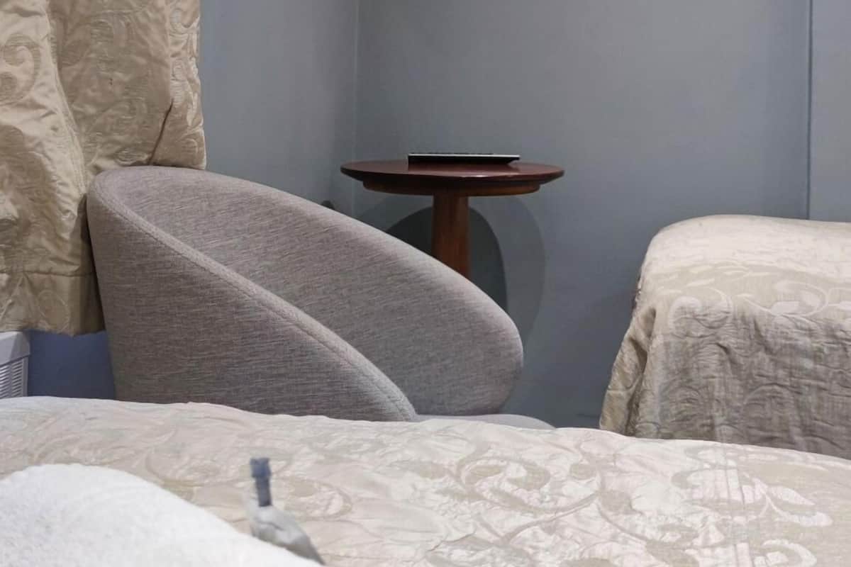 Une chambre d’hôtel avec un lit, un téléviseur fixé au mur, une petite table et un rideau.