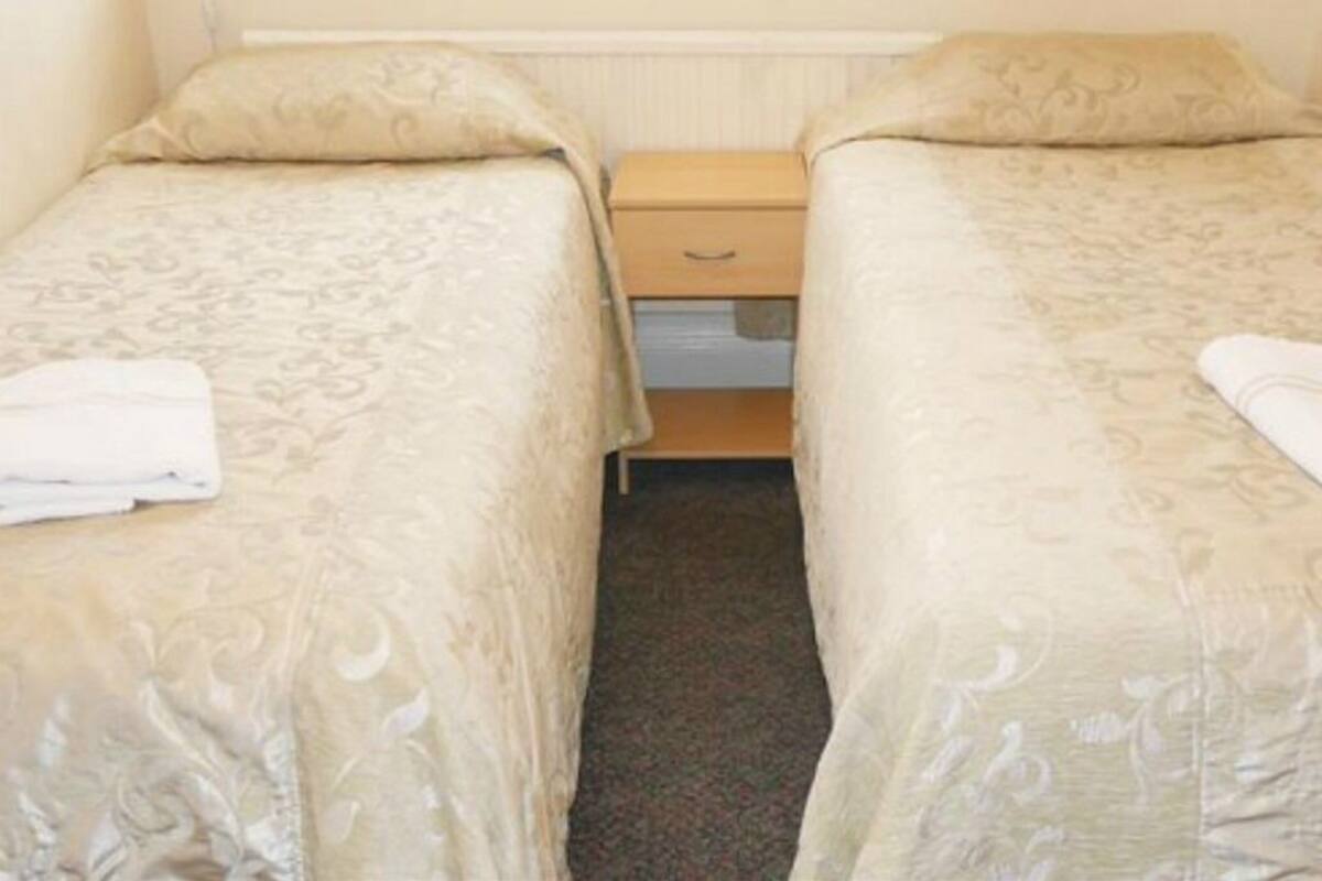 Une chambre double avec deux lits, une table de chevet et une commode.