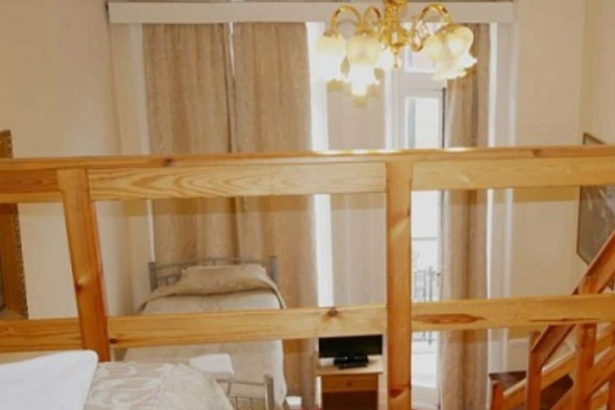 Une chambre avec des lits superposés, un téléviseur et un lustre.