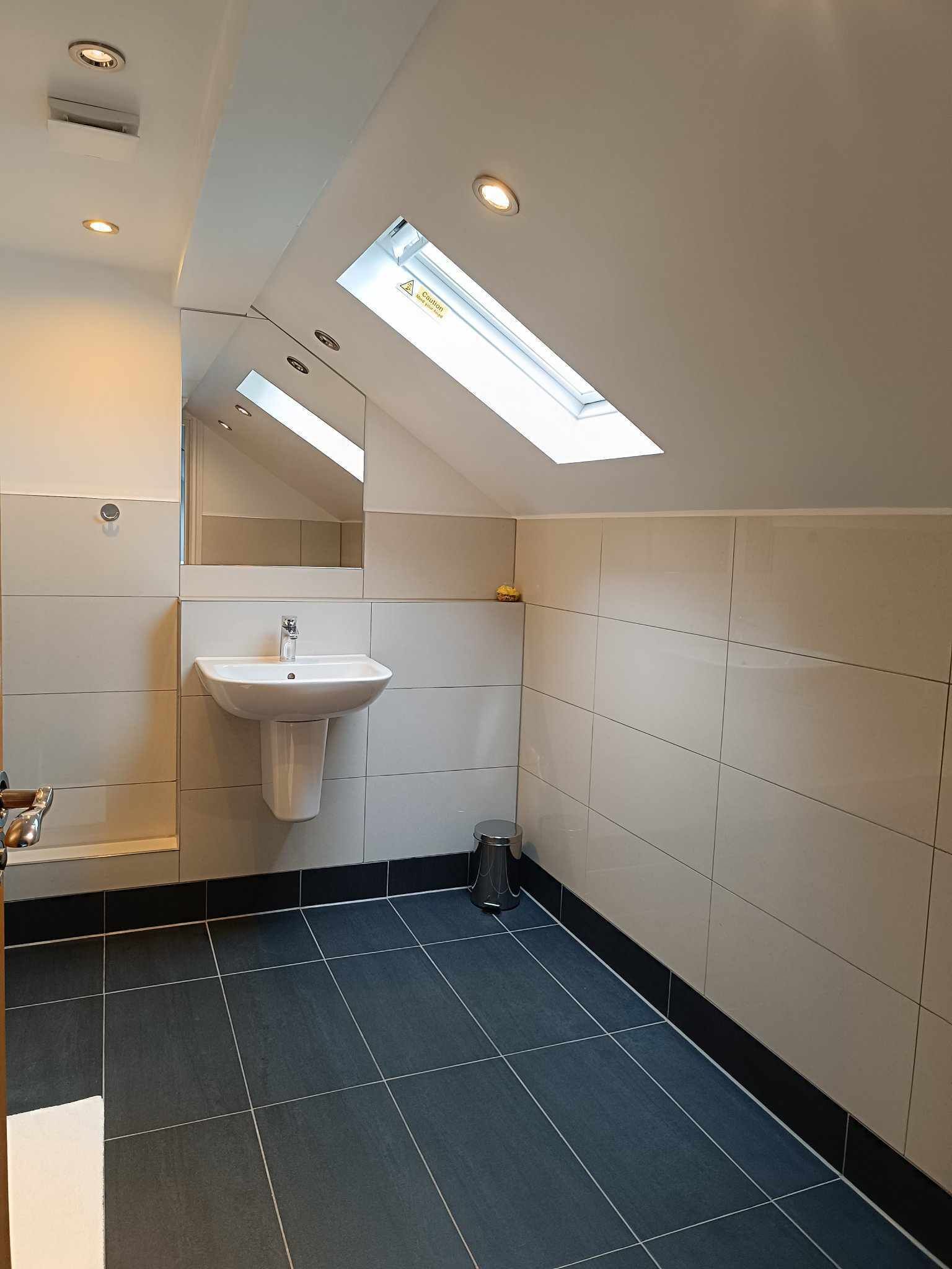 Un baño moderno con tragaluz, un lavabo y un cubo de basura.