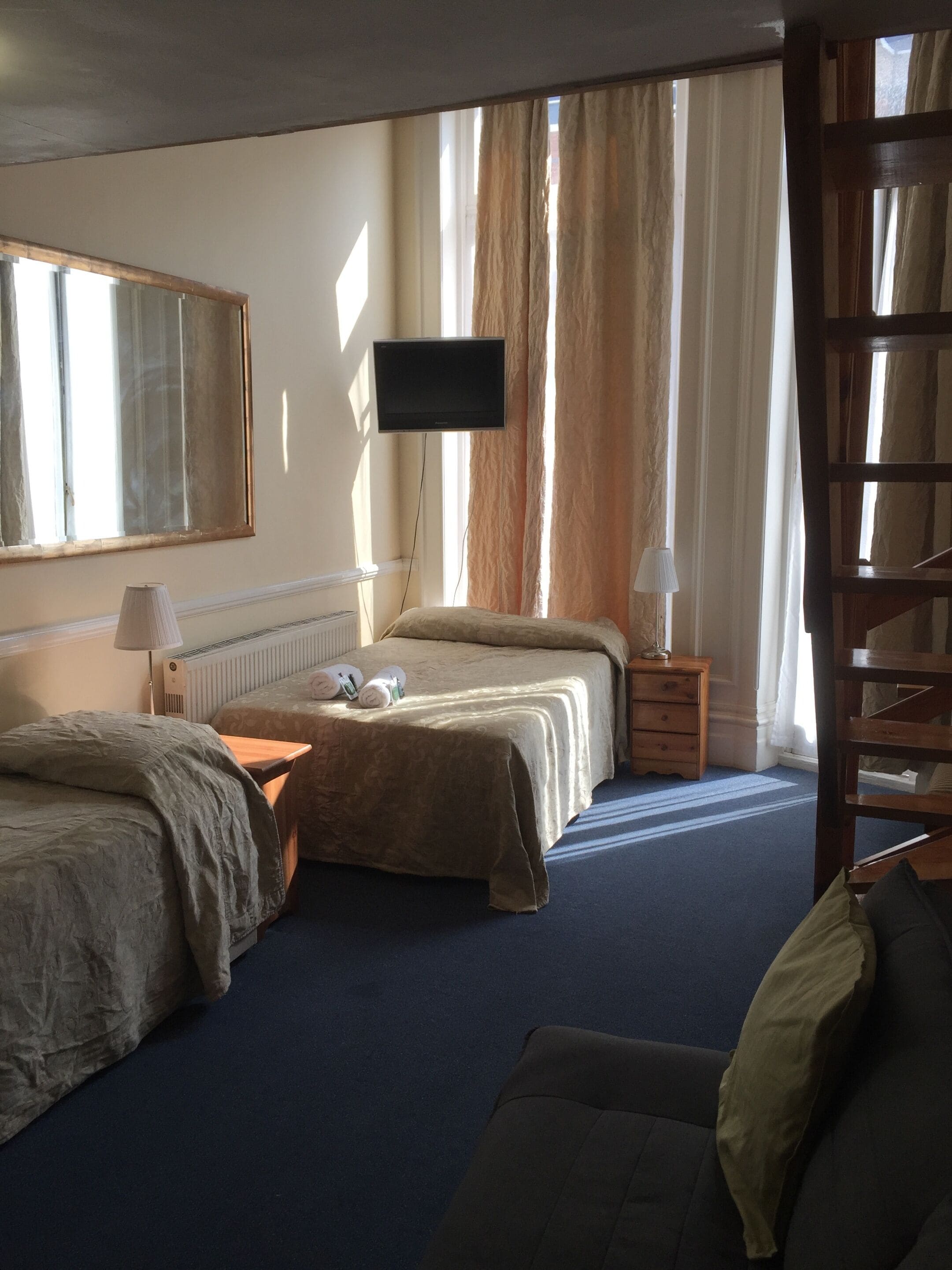 A hotel room with two beds, a TV, a lamp, a small table, and a chair.