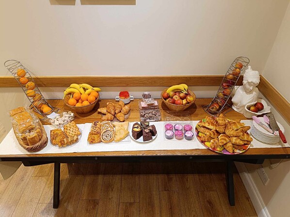 A buffet table with various baked goods, fruits, and pastries. - St Simeon (London)