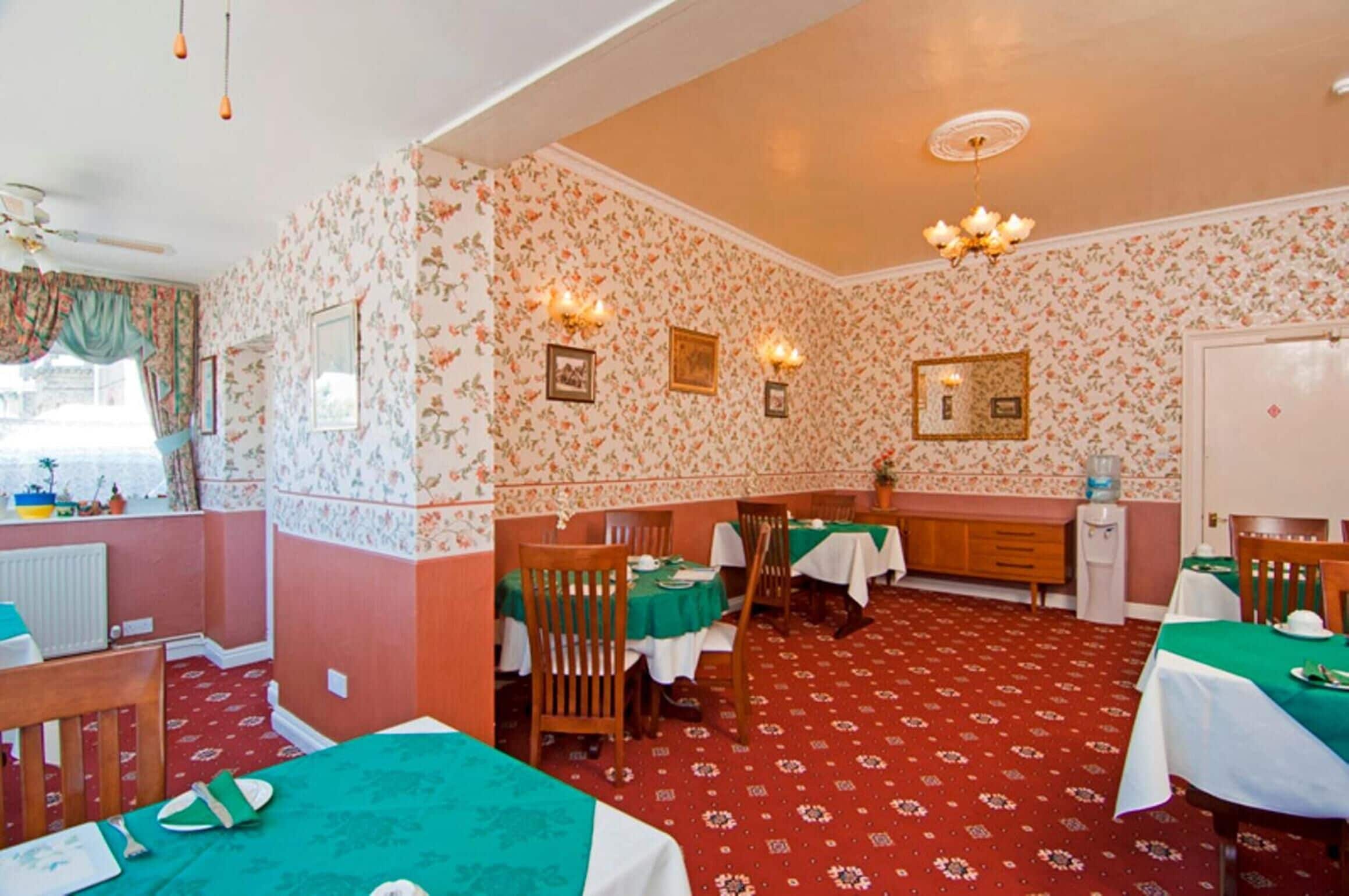Un comedor con mesas dispuestas para comer, una zona de cocina y un radiador.