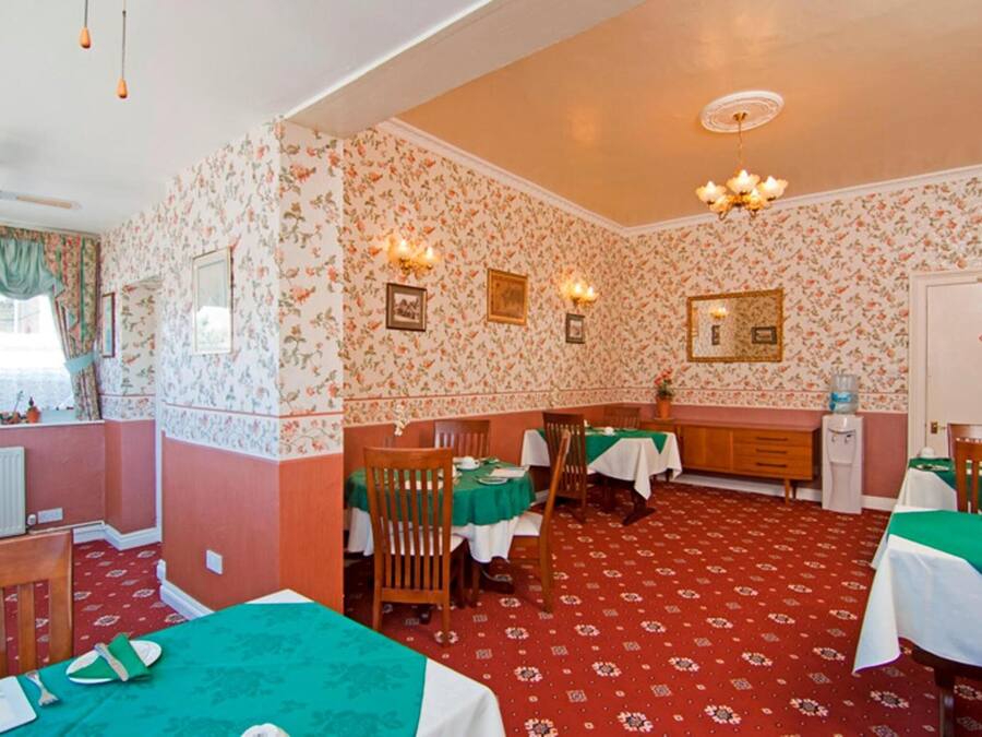 Un comedor con mesas dispuestas para comer, una zona de cocina y un radiador.