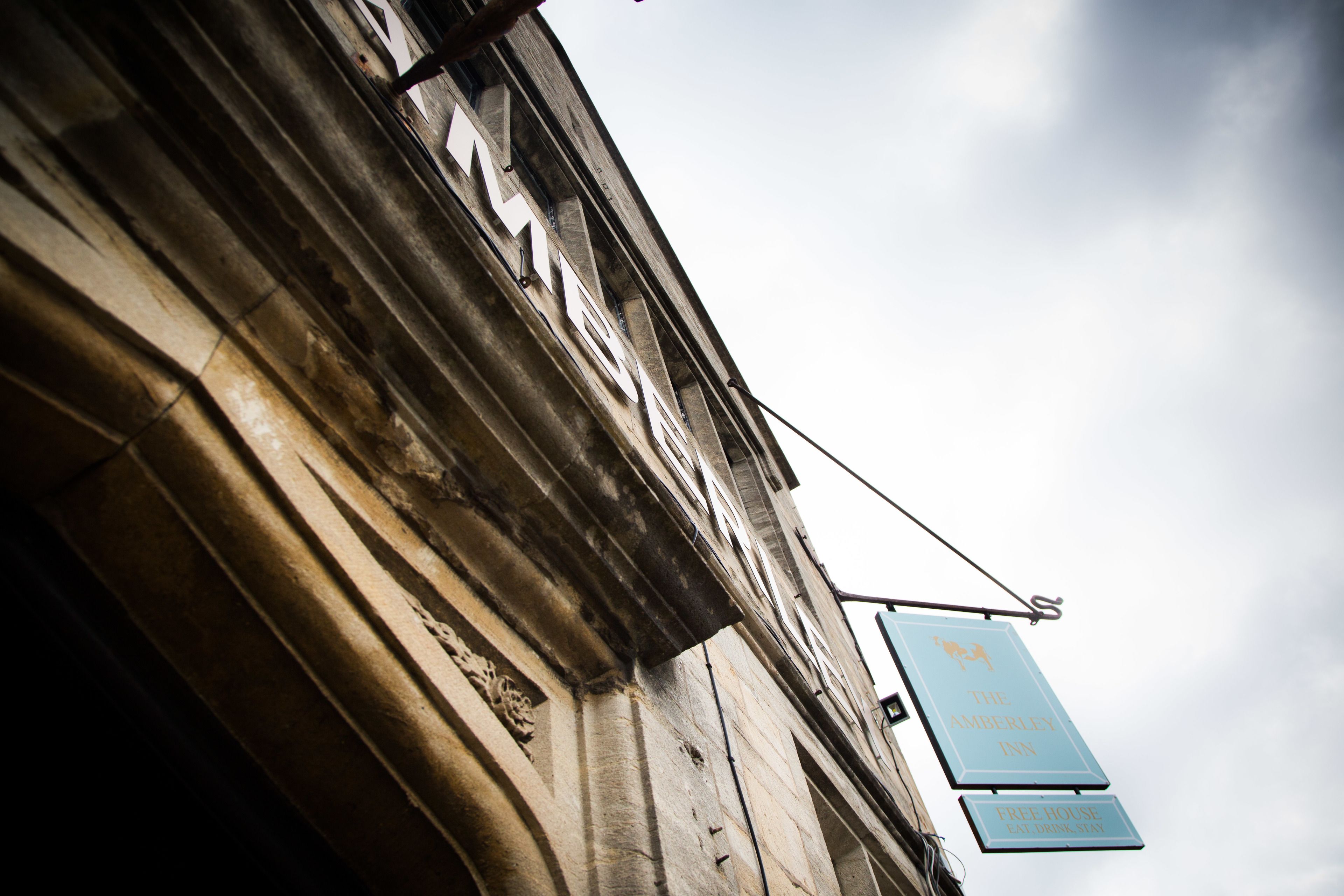 A building with a sign for 'The Amberley Inn' and a 'Free House Eat Drink Stay' sign.