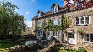 A stone house with multiple windows, a garden, and a small pond. - The Amberley Inn (Stroud)