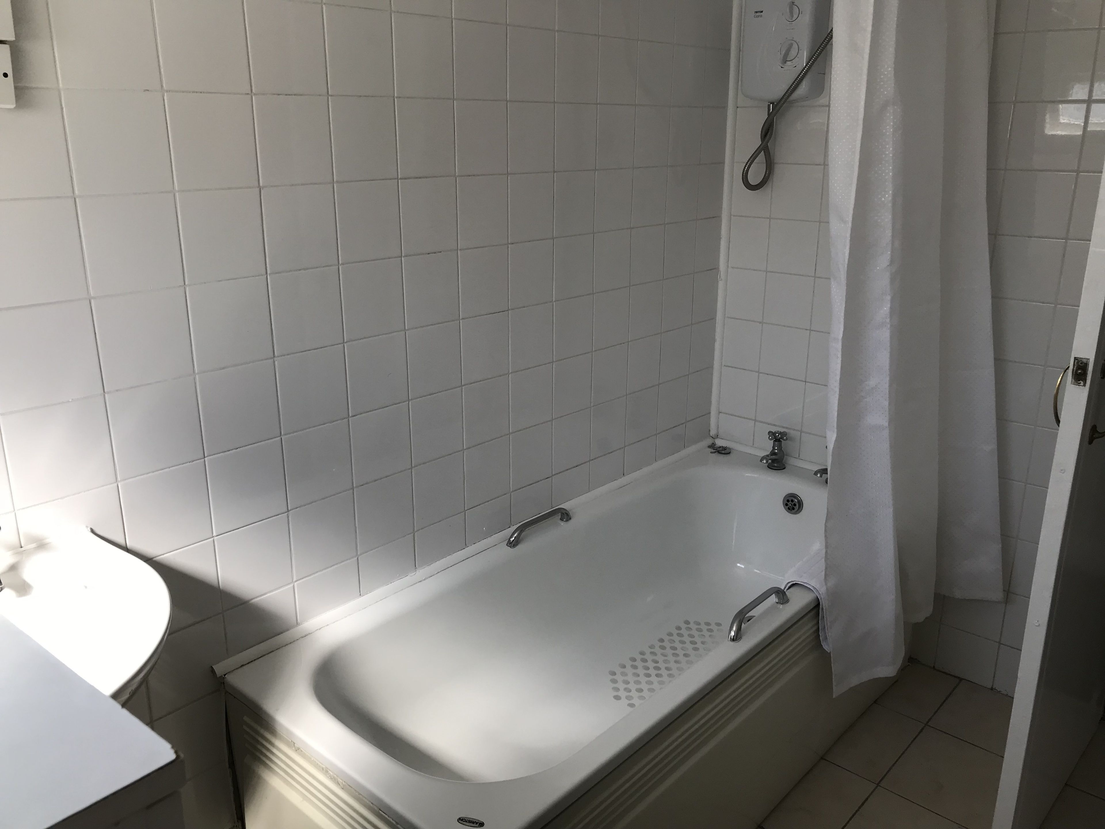 Une salle de bain avec une baignoire blanche, une douche et un lavabo blanc.