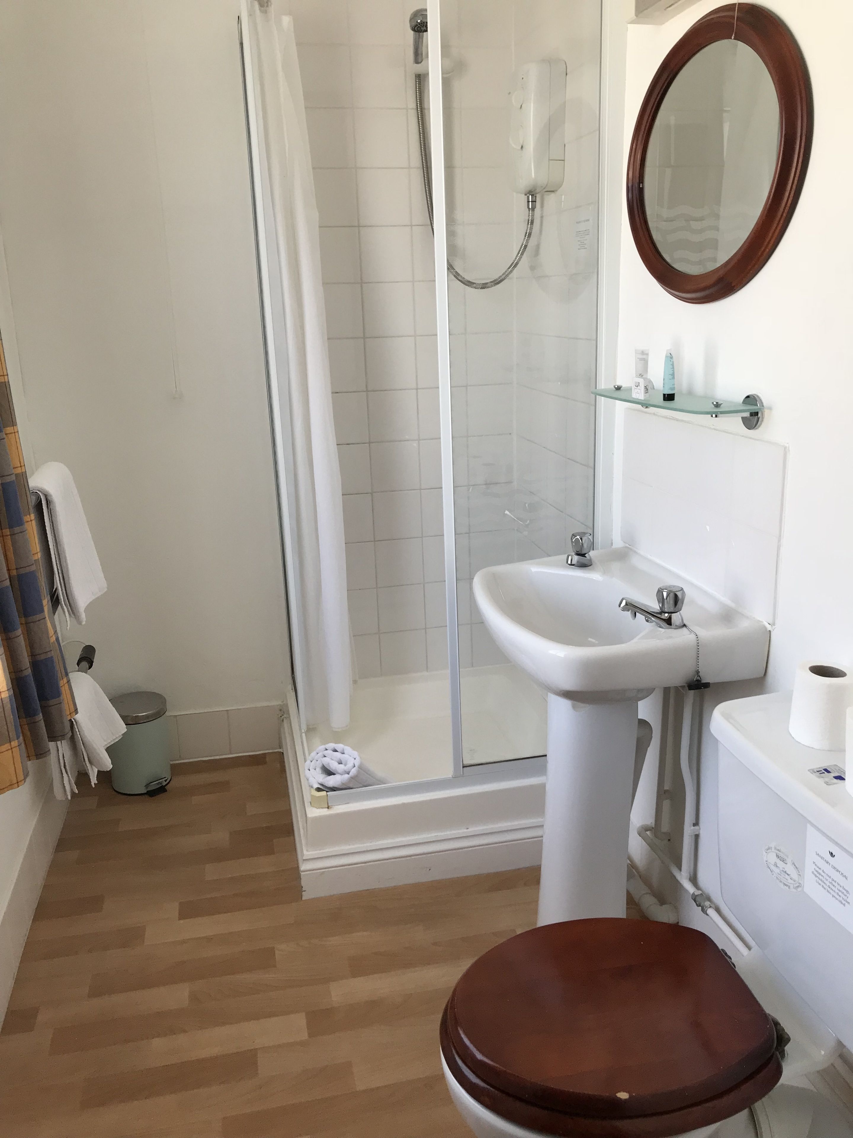 A bathroom with a shower, toilet, sink, and mirror.
