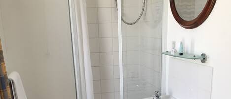 A bathroom with a shower, toilet, sink, and mirror.