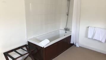A bathroom with a bathtub, a shower, and a towel rack.
