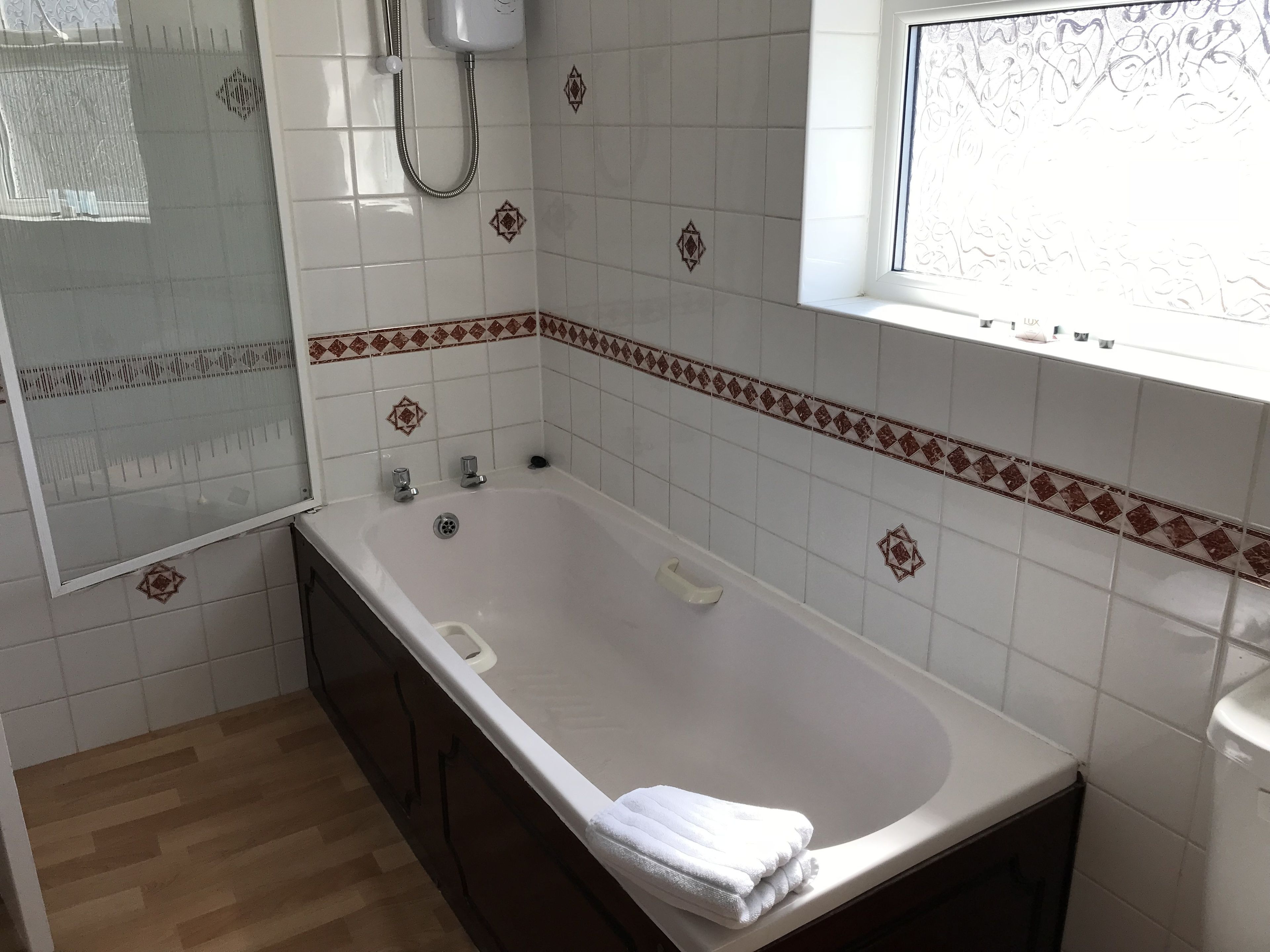 A bathroom with a bathtub, a shower, and a window.