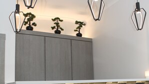 Eine moderne Küche mit Steinrückwand, Holzschränken und Pendelleuchten.