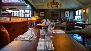 A restaurant interior with wooden tables, clear glassware, and a high ceiling with a central light fixture. - The Dukes Head Hotel (Wallington)