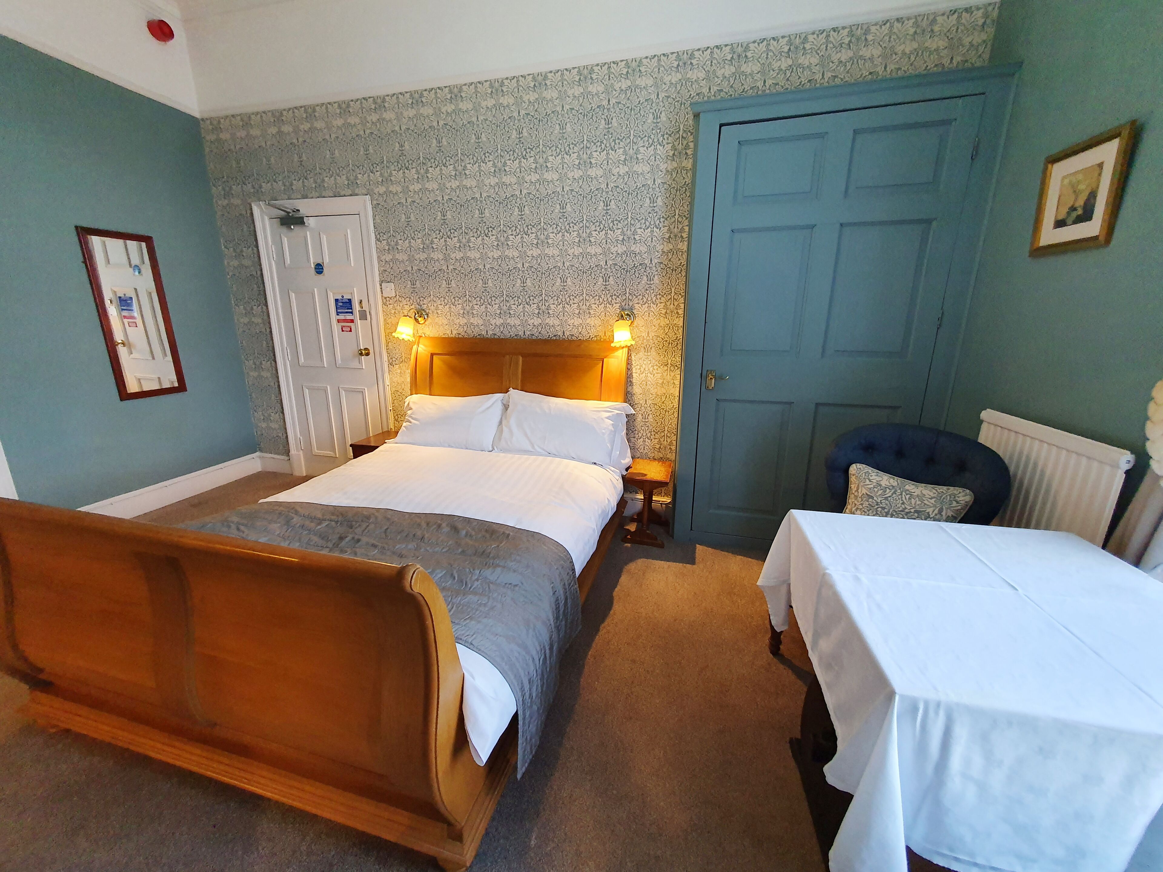 Een slaapkamer met een houten bed, een klein bed, een blauwe deur en een radiator.