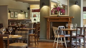 A restaurant interior with wooden furniture, a fireplace, and framed artwork on the walls. - Dartbridge Inn Buckfastleigh by Greene King Inns (Buckfastleigh)