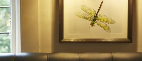 A framed artwork of a dragonfly on a wall.
