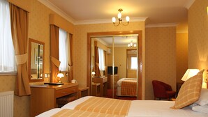 Una camera d'albergo con un letto grande, una scrivania, una sedia, uno specchio e un armadio.