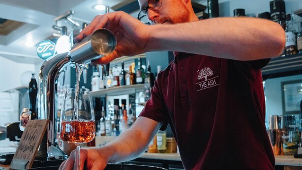 A person pouring a drink into a glass at a bar. - The Ashburnham Hotel (Burry Port)