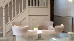 A modern interior with a staircase, two armchairs, a small table with a plant, and a radiator. - Rufford Arms Hotel (Ormskirk)