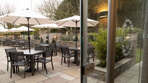 An outdoor patio with tables and chairs, umbrellas, and a stone wall. - Rufford Arms Hotel (Ormskirk)