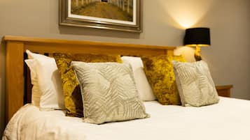 A neatly made bed with a variety of pillows and a framed picture above it.