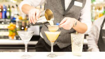 A bartender pouring a drink into a martini glass.