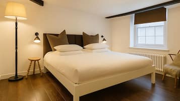 A neatly arranged bedroom with a bed, bedside lamps, a chair, and a window with a view.