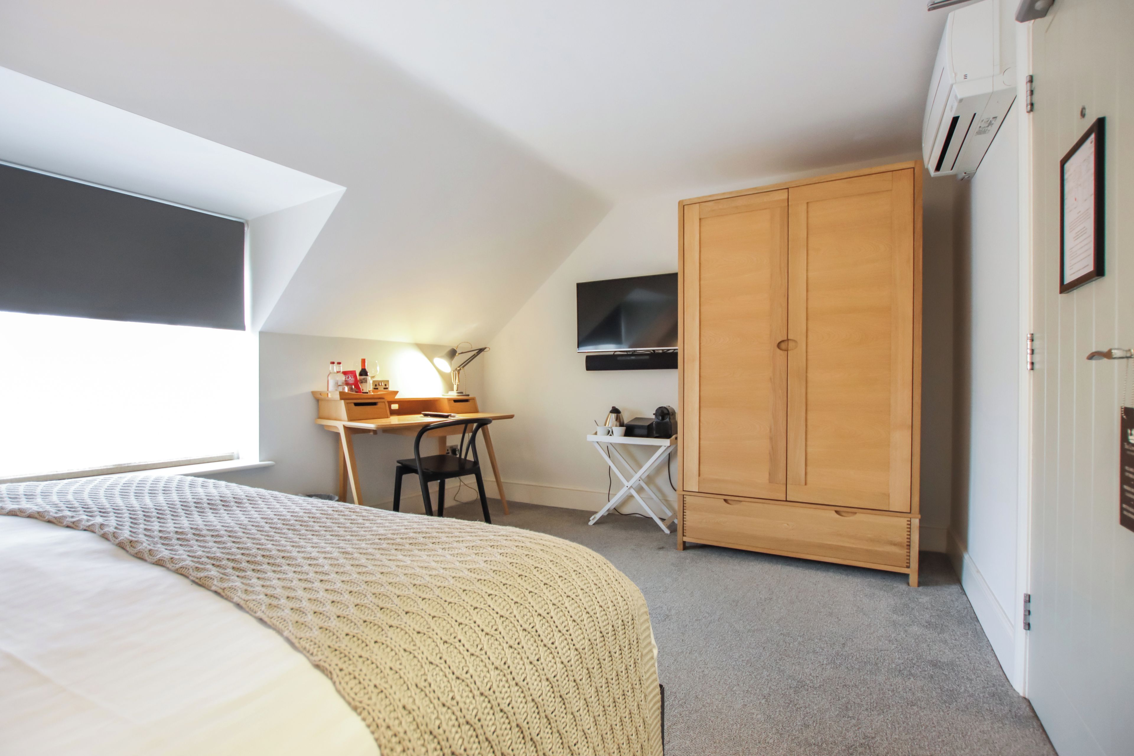 A bedroom with a bed, a desk, a chair, a wardrobe, and a television.