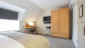 A bedroom with a bed, a desk, a chair, a wardrobe, and a television.