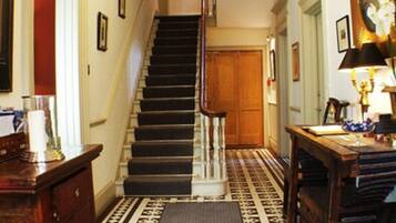 A staircase with a patterned carpet leading to a landing with a chandelier.