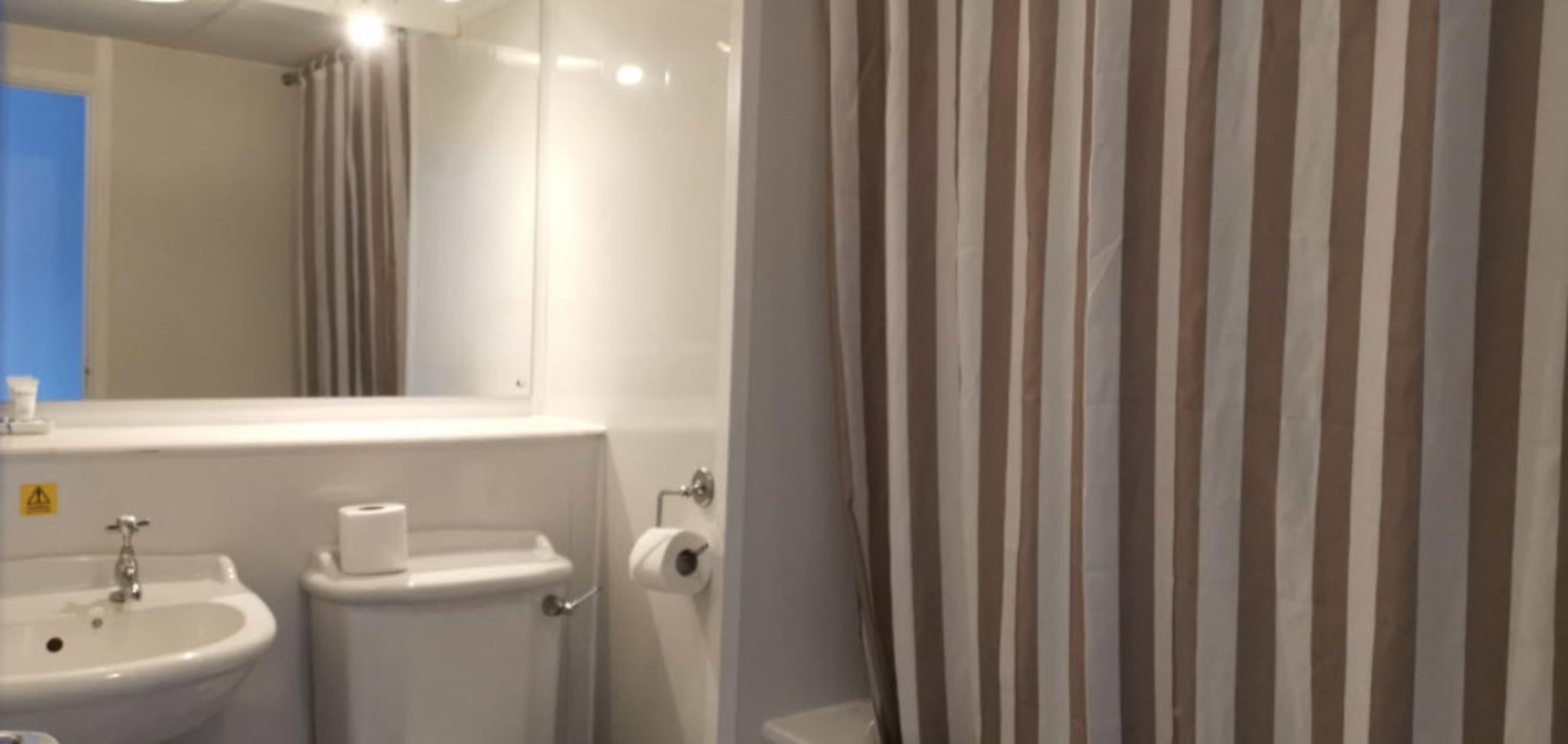 A bathroom with a sink, toilet, and a mirror.