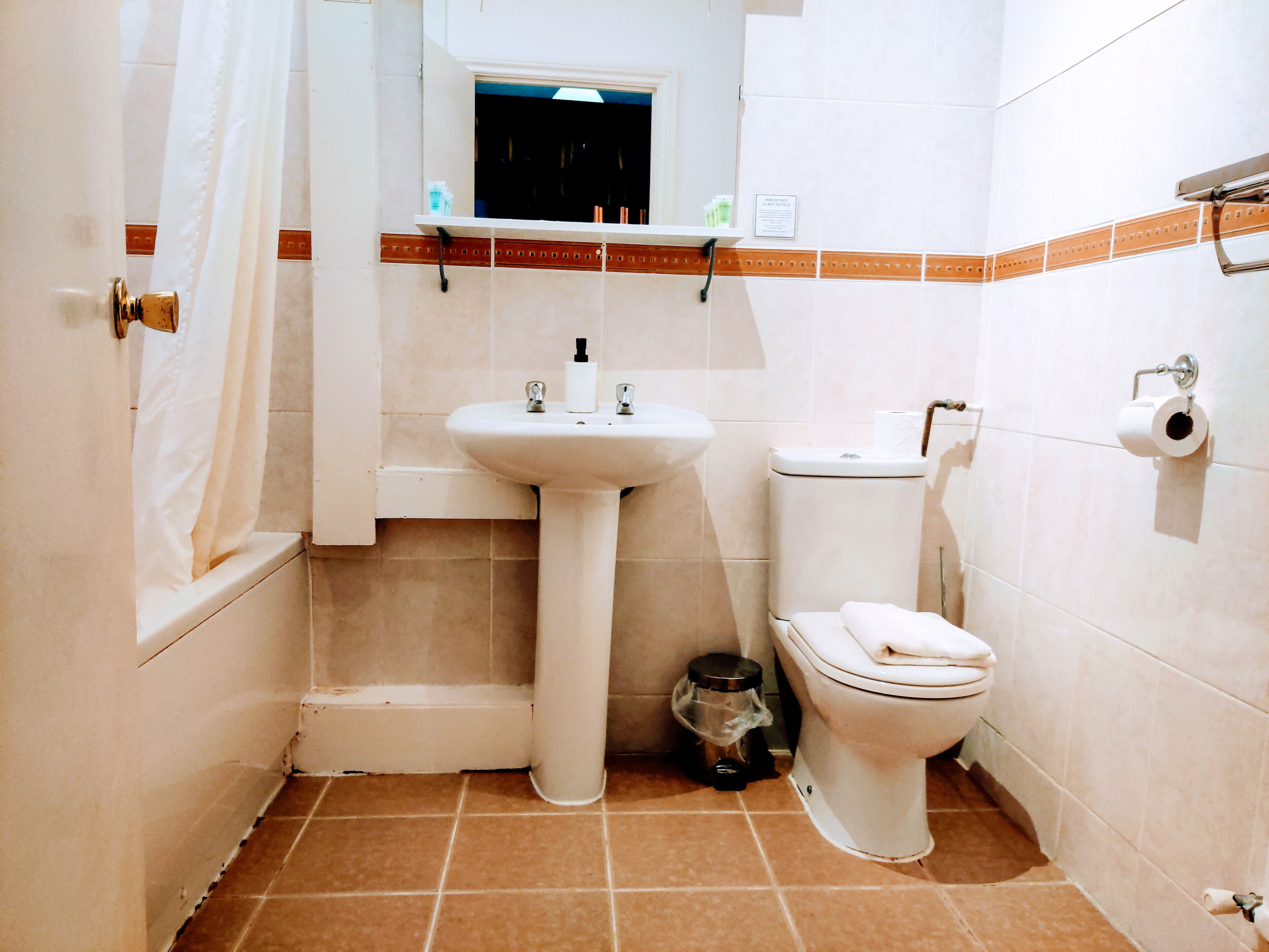 A bathroom with a sink, toilet, and a trash bin.