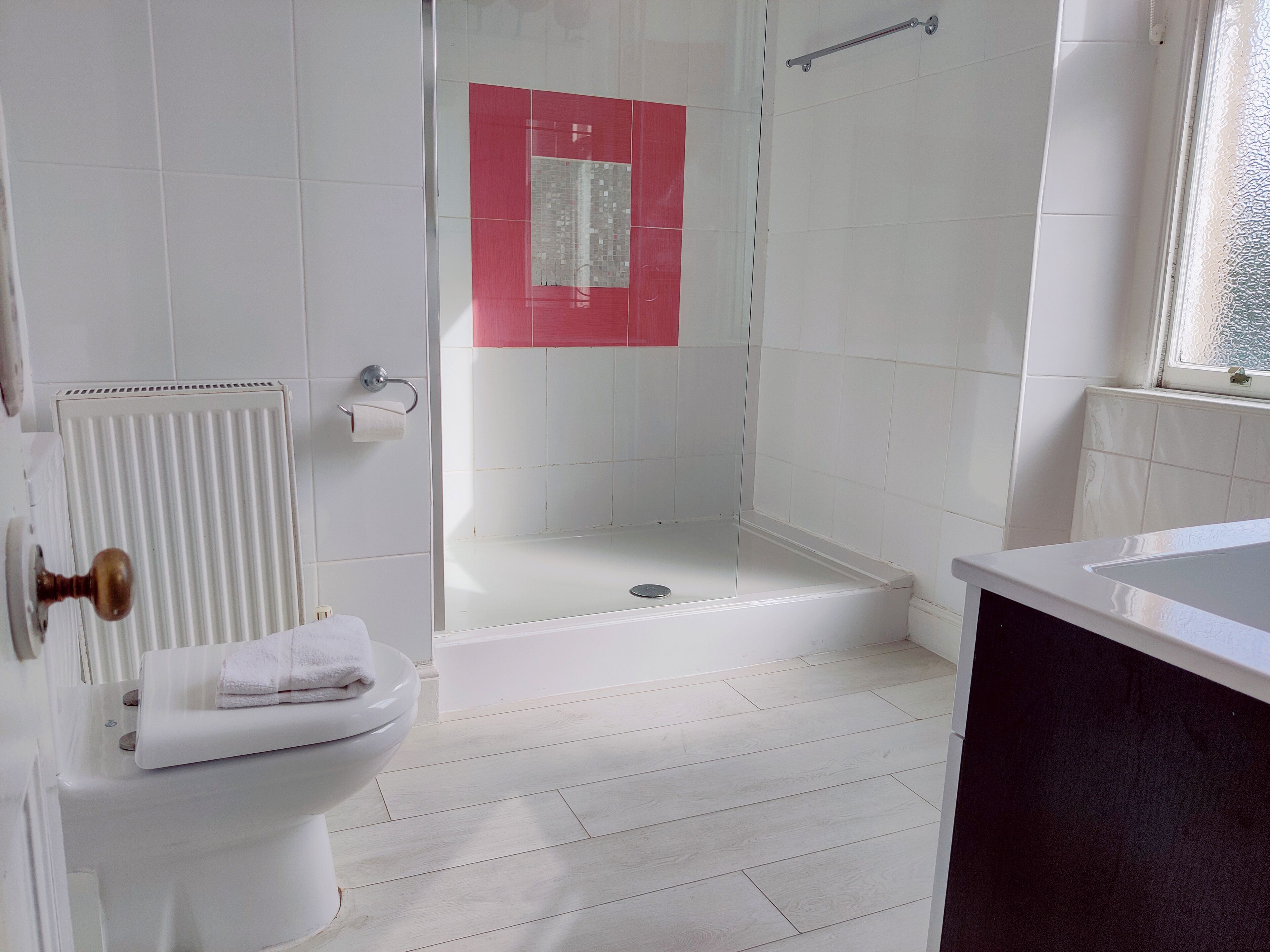 A bathroom with a toilet, shower, and sink.